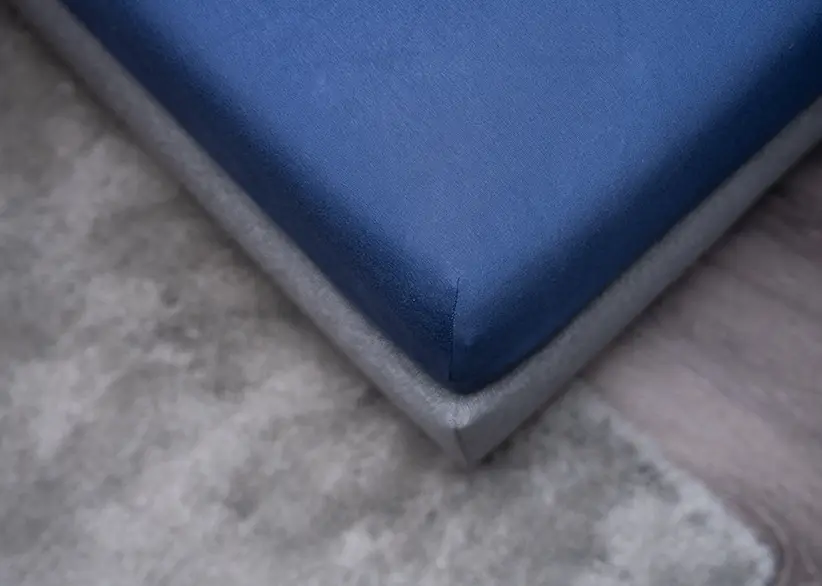 Eck-Nahaufnahme einer Premium Spannbetttuch in dunkelblau gespannt auf einer Matratze